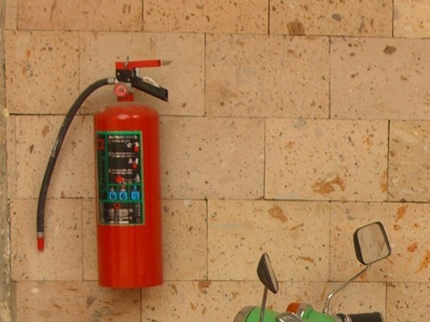 Red fire extinguisher mounted on a sandstone block wall