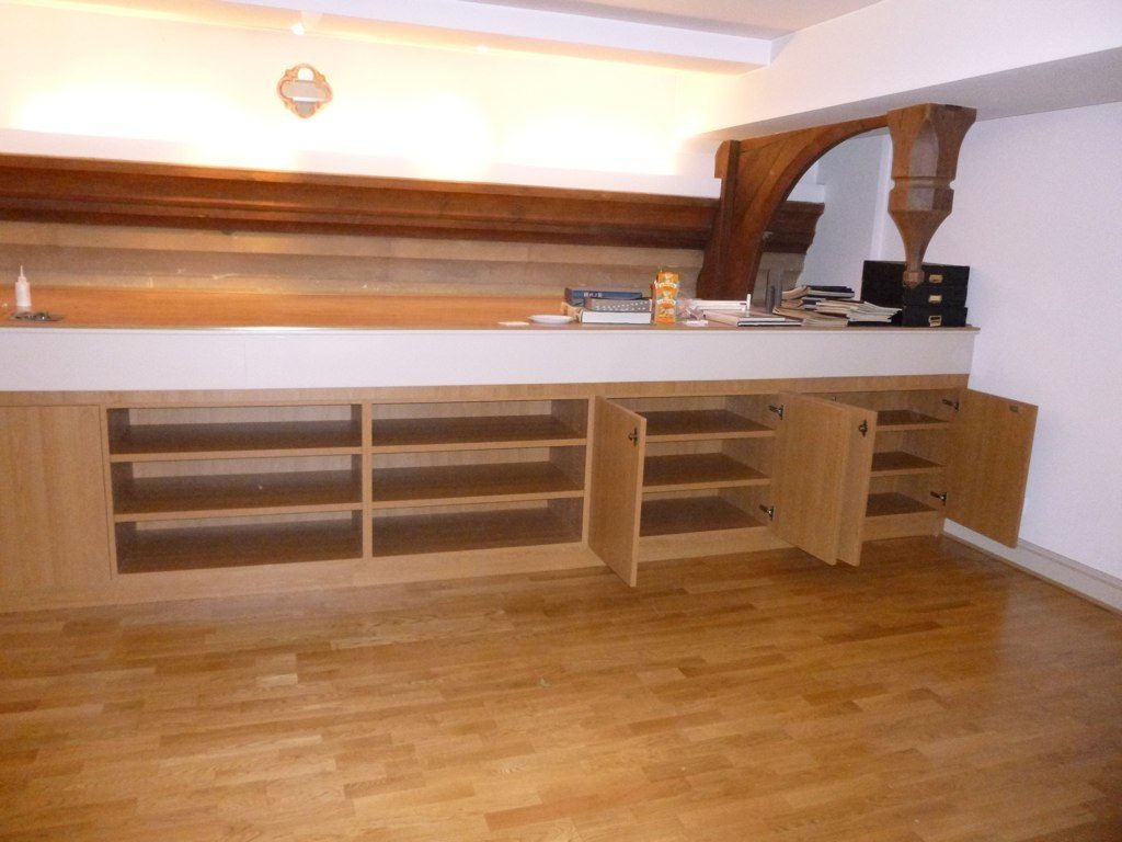 Sunlit room with honey toned wood flooring and a long built-in cabinet